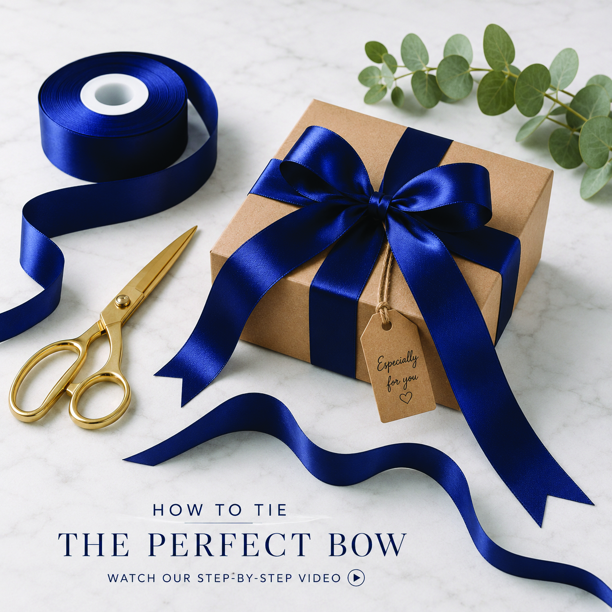 Kraft gift box wrapped with navy satin ribbon tied into a perfect gift bow beside a ribbon roll and gold scissors.